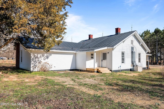 exterior space featuring a front yard, a standing seam roof, metal roof, and a chimney