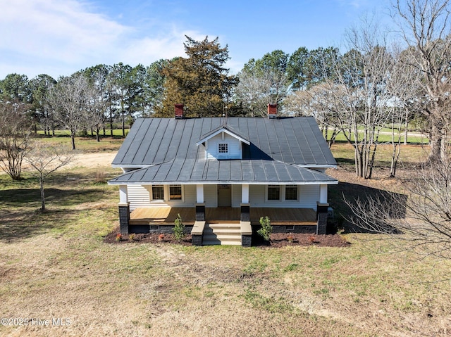 view of front facade featuring a standing seam roof, metal roof, covered porch, and a front yard