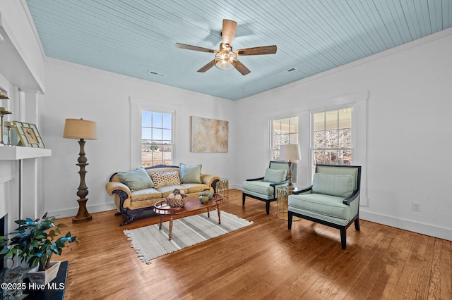 living room with crown molding, wood-type flooring, visible vents, and plenty of natural light