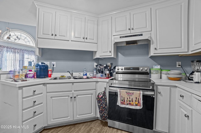 kitchen with light countertops, stainless steel range with electric cooktop, under cabinet range hood, white cabinetry, and a sink