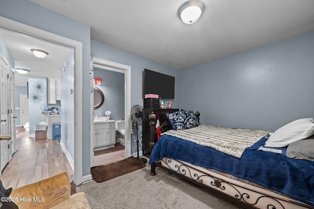 bedroom featuring light wood-type flooring, baseboards, and ensuite bathroom