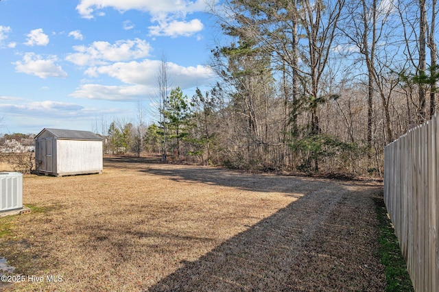 view of yard with an outbuilding, central AC, fence, and a shed