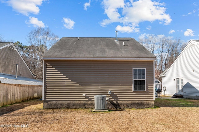 rear view of house featuring a lawn, fence, and central air condition unit