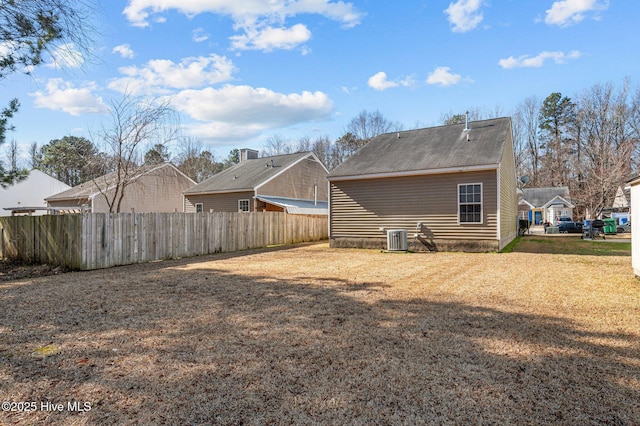 rear view of house featuring a residential view, fence, a lawn, and central air condition unit