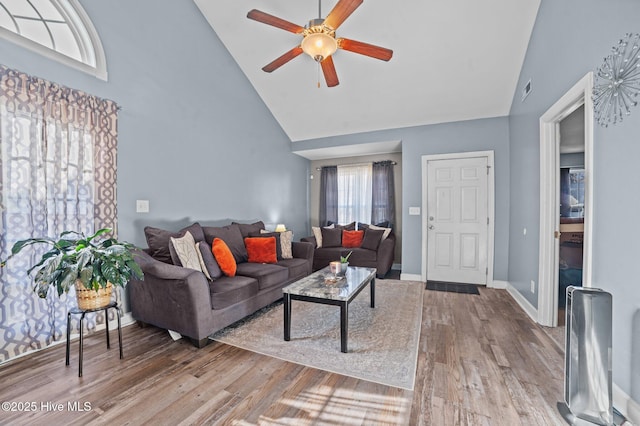 living room featuring visible vents, ceiling fan, high vaulted ceiling, light wood-type flooring, and baseboards