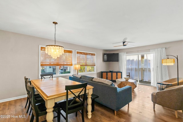 dining area featuring ceiling fan with notable chandelier, wood finished floors, and baseboards