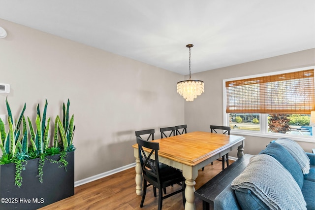 dining space featuring a notable chandelier, baseboards, and wood finished floors