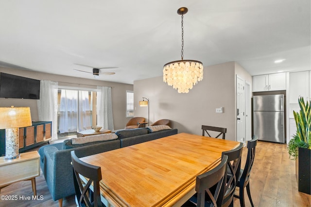 dining room featuring ceiling fan with notable chandelier and light wood-style flooring