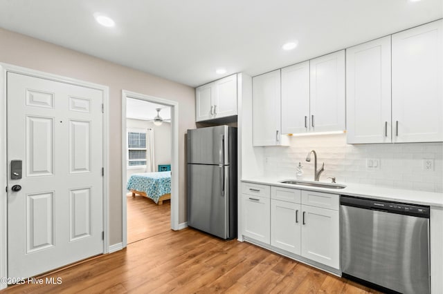 kitchen featuring light countertops, appliances with stainless steel finishes, light wood-style floors, white cabinets, and a sink