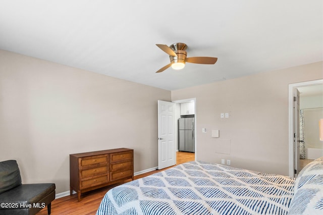 bedroom featuring a ceiling fan, light wood-type flooring, freestanding refrigerator, and baseboards