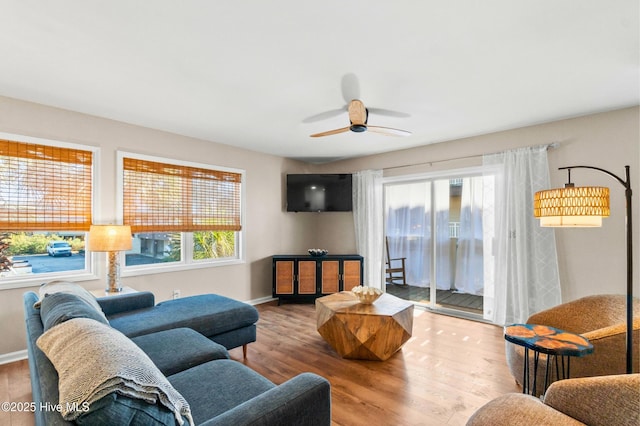 living room with ceiling fan, baseboards, and wood finished floors