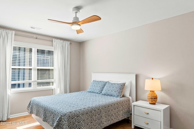 bedroom featuring a ceiling fan, baseboards, visible vents, and wood finished floors