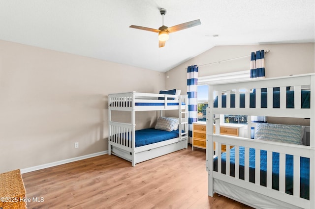 bedroom featuring ceiling fan, vaulted ceiling, baseboards, and wood finished floors