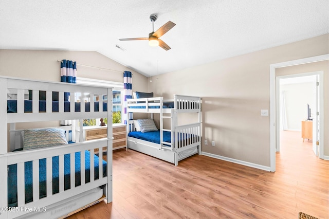 bedroom featuring lofted ceiling, a textured ceiling, wood finished floors, visible vents, and baseboards