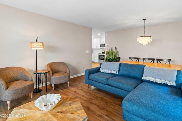 living room featuring a chandelier, light wood-type flooring, and baseboards