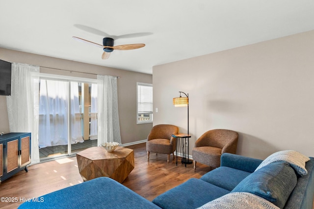 living room with wood finished floors, a ceiling fan, and baseboards