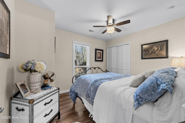 bedroom with baseboards, visible vents, a ceiling fan, dark wood finished floors, and a closet