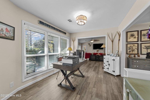 office space featuring baseboards, visible vents, and wood finished floors