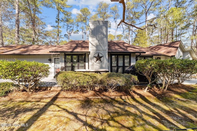 view of front of property with a front yard, a chimney, and an attached garage