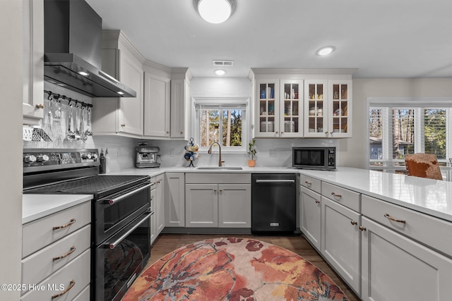 kitchen featuring black dishwasher, wall chimney exhaust hood, built in microwave, light countertops, and double oven range