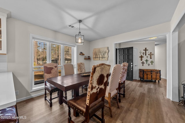 dining space featuring wood finished floors, visible vents, and baseboards