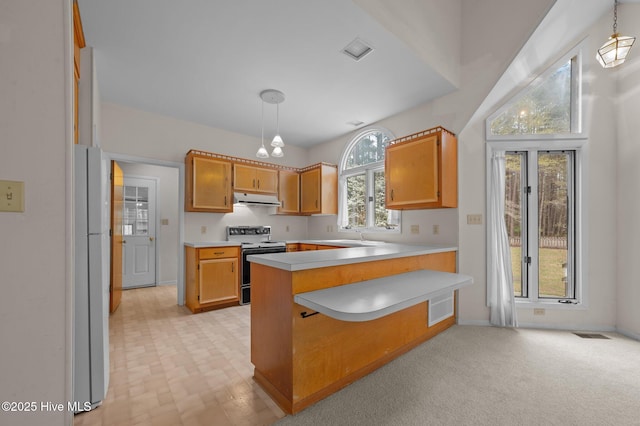 kitchen with light countertops, freestanding refrigerator, a peninsula, under cabinet range hood, and electric stove