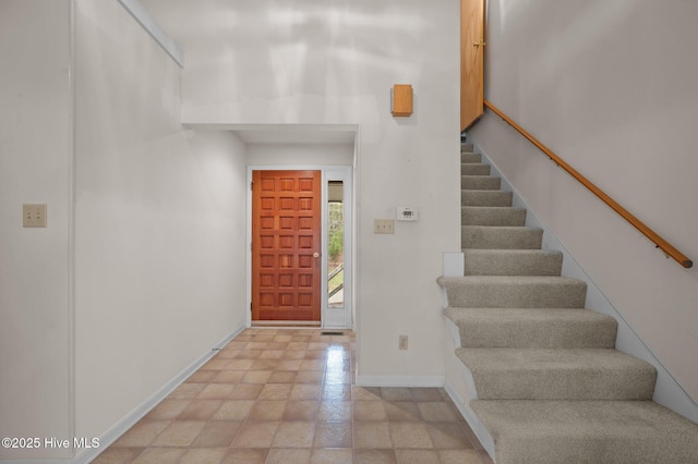 foyer entrance with baseboards and stairway