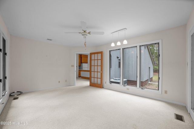 carpeted empty room featuring baseboards, visible vents, and a ceiling fan