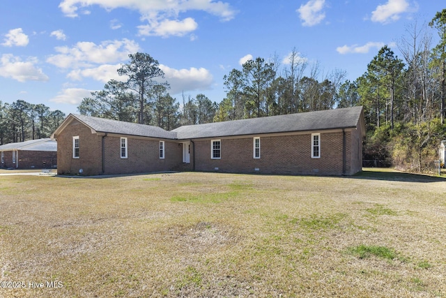 rear view of property featuring crawl space, brick siding, and a lawn