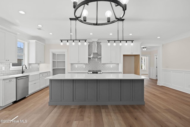 kitchen featuring wall chimney range hood, a center island, white cabinetry, and stainless steel dishwasher