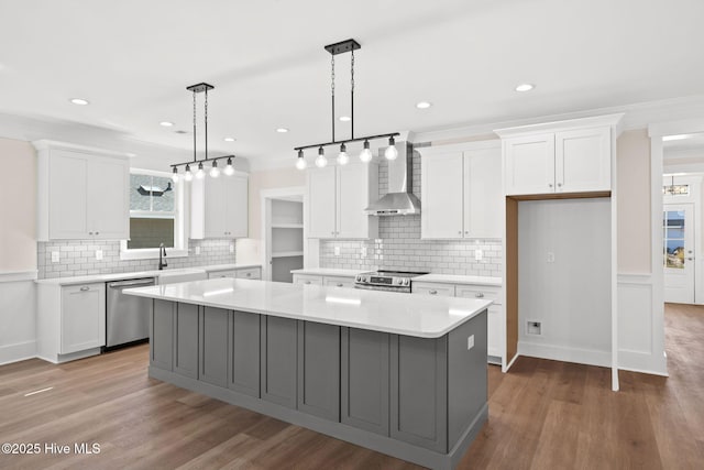 kitchen with white cabinets, a center island, stainless steel appliances, and wall chimney exhaust hood