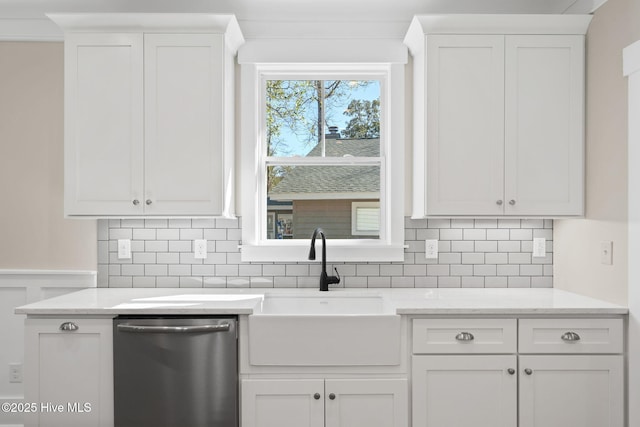 kitchen featuring sink, white cabinetry, stainless steel dishwasher, light stone countertops, and decorative backsplash