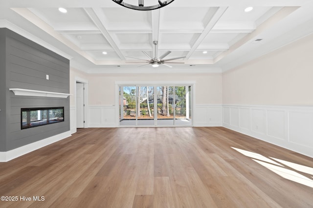 unfurnished living room with coffered ceiling, light hardwood / wood-style flooring, a large fireplace, and beam ceiling