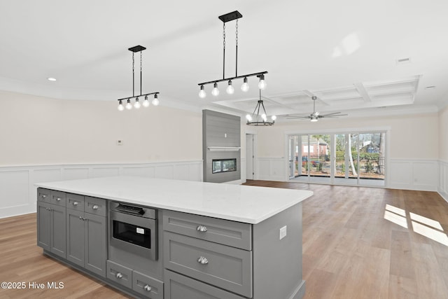 kitchen featuring stainless steel microwave, hanging light fixtures, gray cabinetry, and a center island