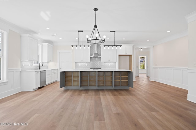 kitchen with a kitchen island, white cabinets, hanging light fixtures, and wall chimney exhaust hood