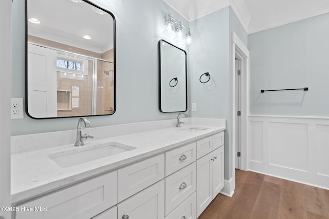 bathroom featuring wood-type flooring, vanity, ornamental molding, and a shower with door