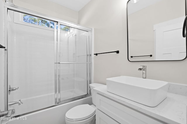 full bathroom featuring vanity, combined bath / shower with glass door, and toilet