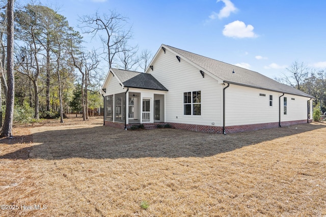 rear view of house featuring a yard and a sunroom