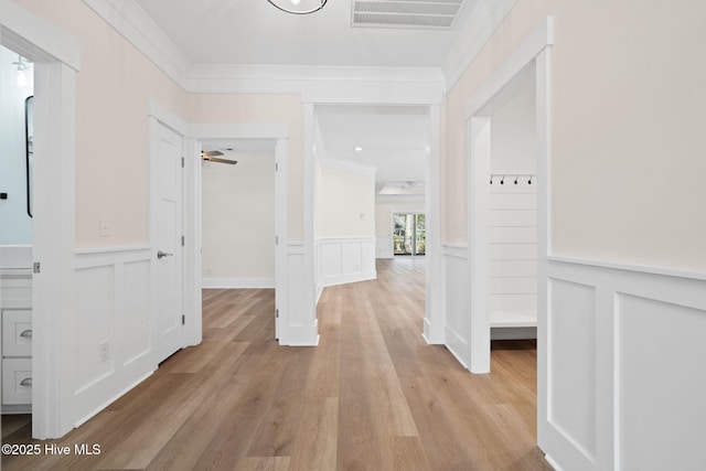 hallway featuring light wood-type flooring and ornamental molding