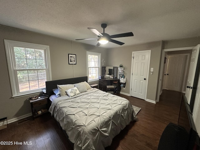 bedroom with a textured ceiling, ceiling fan, dark wood finished floors, and baseboards