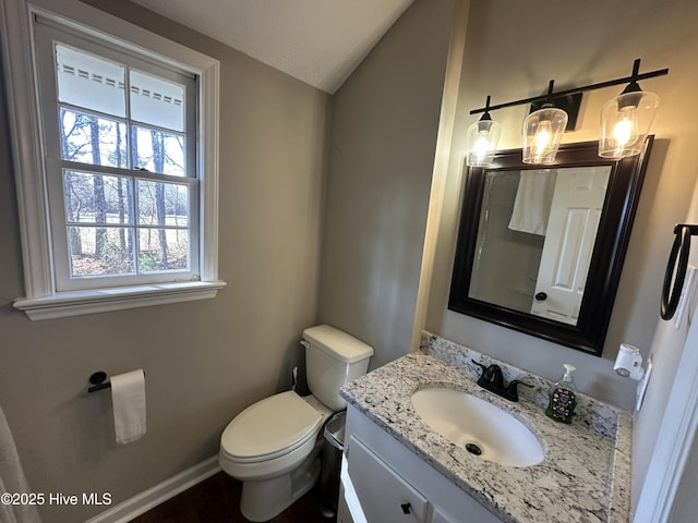 bathroom with baseboards, vaulted ceiling, vanity, and toilet