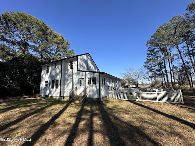 exterior space featuring entry steps, a lawn, and fence