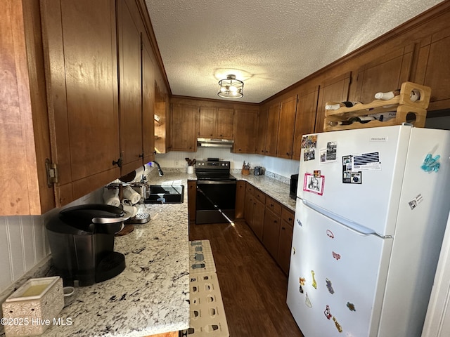 kitchen with under cabinet range hood, electric range, a sink, freestanding refrigerator, and dark wood finished floors