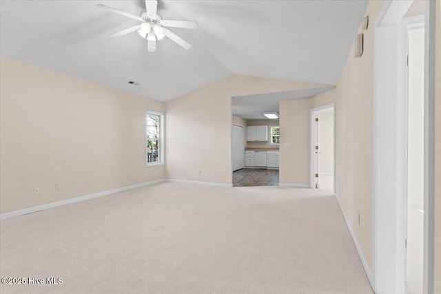 unfurnished living room featuring baseboards, visible vents, a ceiling fan, vaulted ceiling, and carpet flooring