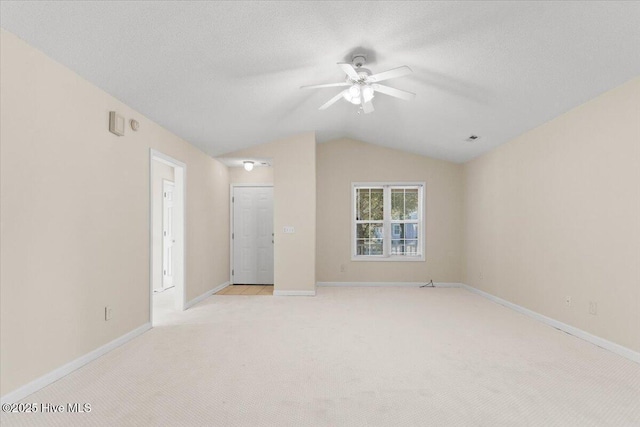 unfurnished bedroom featuring baseboards, vaulted ceiling, a textured ceiling, and light colored carpet