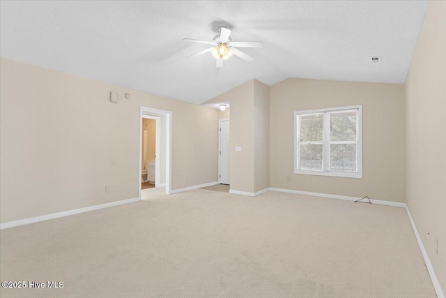 spare room with vaulted ceiling, ceiling fan, light colored carpet, and baseboards