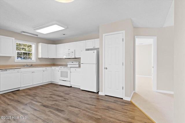 kitchen featuring white appliances, white cabinetry, light countertops, and dark wood-style flooring