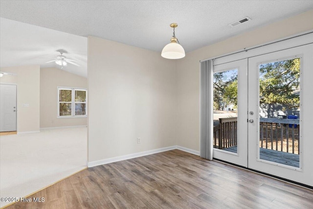 spare room featuring a textured ceiling, french doors, plenty of natural light, and wood finished floors