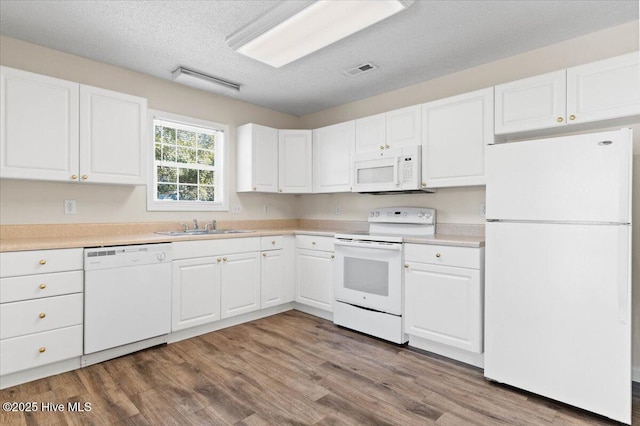 kitchen featuring light countertops, visible vents, white cabinets, a sink, and white appliances