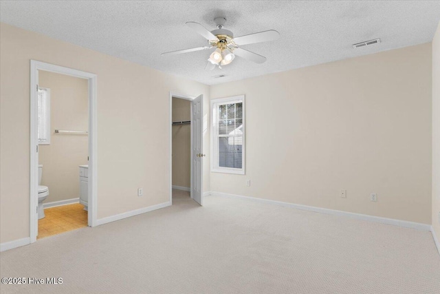 unfurnished bedroom featuring light colored carpet, visible vents, a textured ceiling, and baseboards